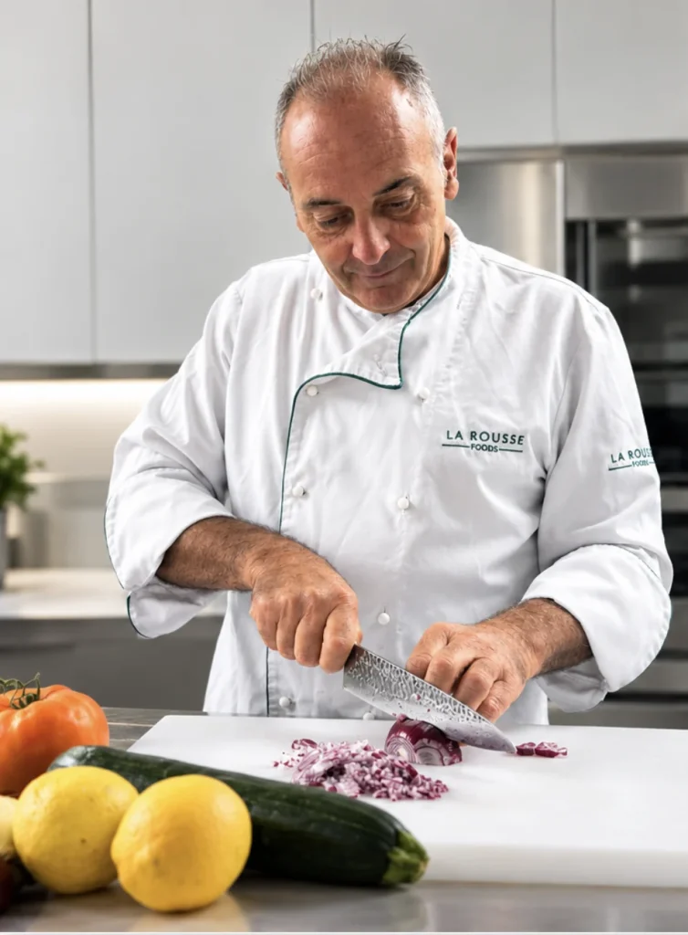 Arnaud Mary, chef à domicile, émince un oignon rouge en cuisine