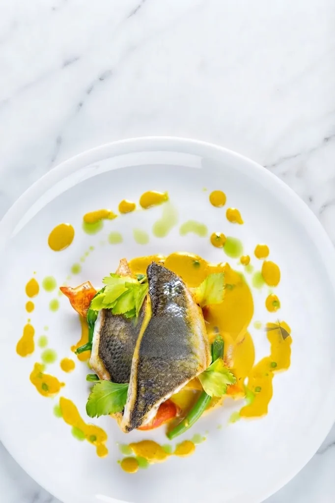 Filet de bar rôti, sauce safranée et légumes, servi à l'assiette